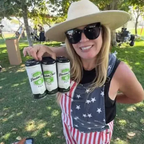 A customer in flag overalls carrying four cans of Freedom Juice