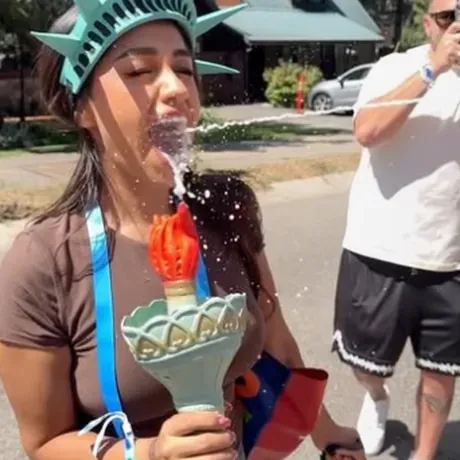 A festival-goer in a Statue of Liberty crown taking a shot of Freedom Juice from the Liberty torch