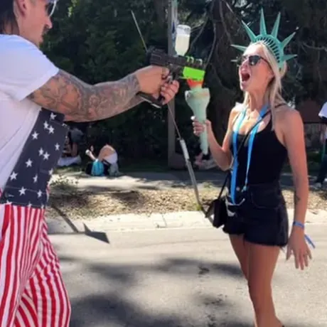 A Freedom Juice pourer in flag pants spraying Freedom Juice from the torch